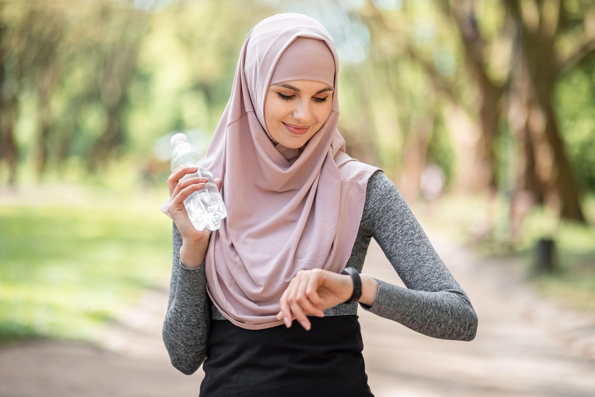 Woman in hijab checking pulse on smart watch after run